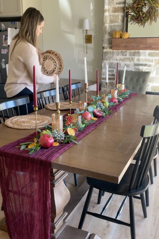 Holding a round woven placemat to start the place settings